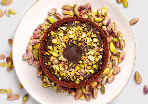 Dubai chocolate cheesecake with pistachio kernels on a kitchen ceramic plate close-up. Top view